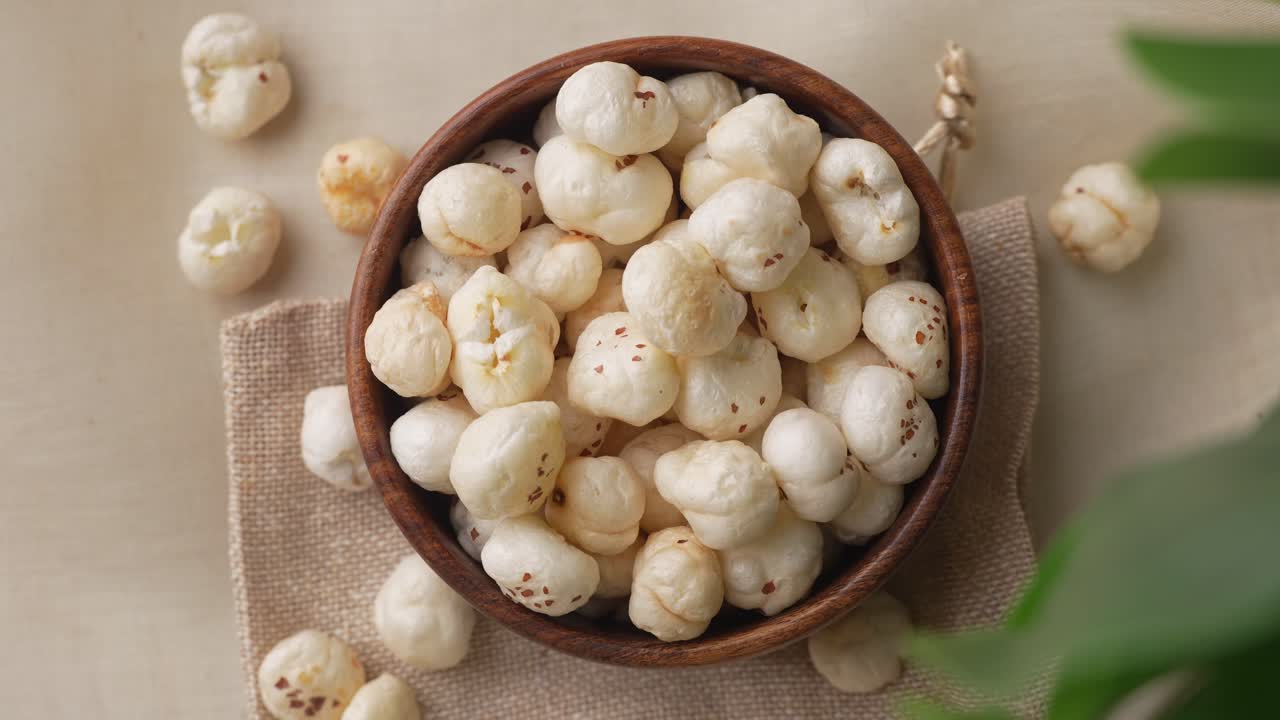 Close-upopname van makhana in een houten kom die door bladeren inzoomt
