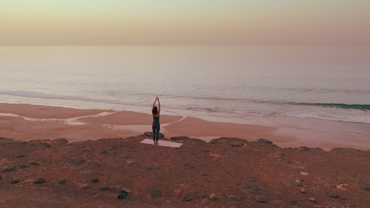 Donna che pratica yoga su una spiaggia all'alba