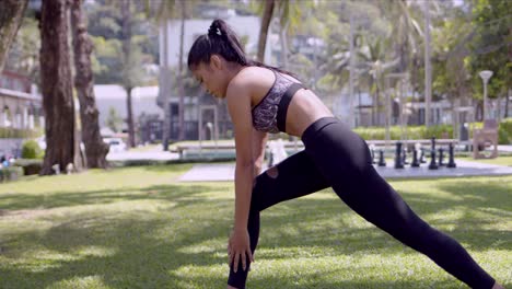 mujer asiática activa estirándose diligentemente en el parque