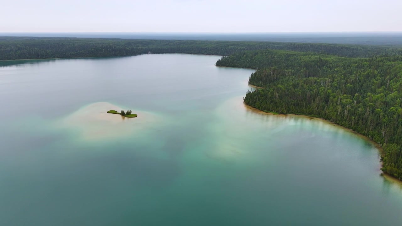 Luftfoto af en græsklædt sandø omgivet af turkist vand og tæt boreal skov ved Big Skunk Lake i det nordlige Ontario