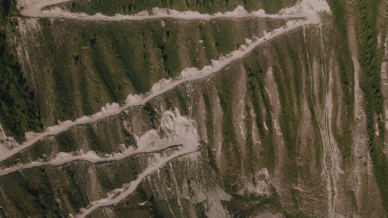Riprese aeree dall'alto della tortuosa strada sterrata al Passo Katu-Yaryk sopra la Valle del Chulyshman, Repubblica dell'Altai, Russia, che mostrano scogliere aspre e taiga.