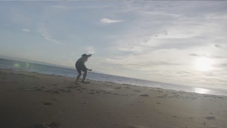 dancer on beach low angle doing jump