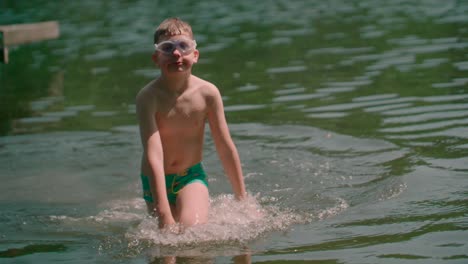 niño vestido con gafas cortas para protección ocular caminando hacia la orilla desde el lago