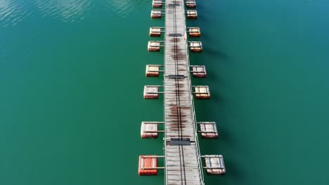 forward moving aerial view of floating pontoon bridge in the middle of a peaceful turquoise lake called lake okutama in tokyo