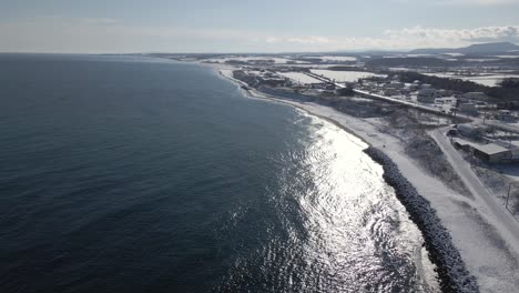 雪と町で冬に日本の海岸線に沿って飛行するドローン