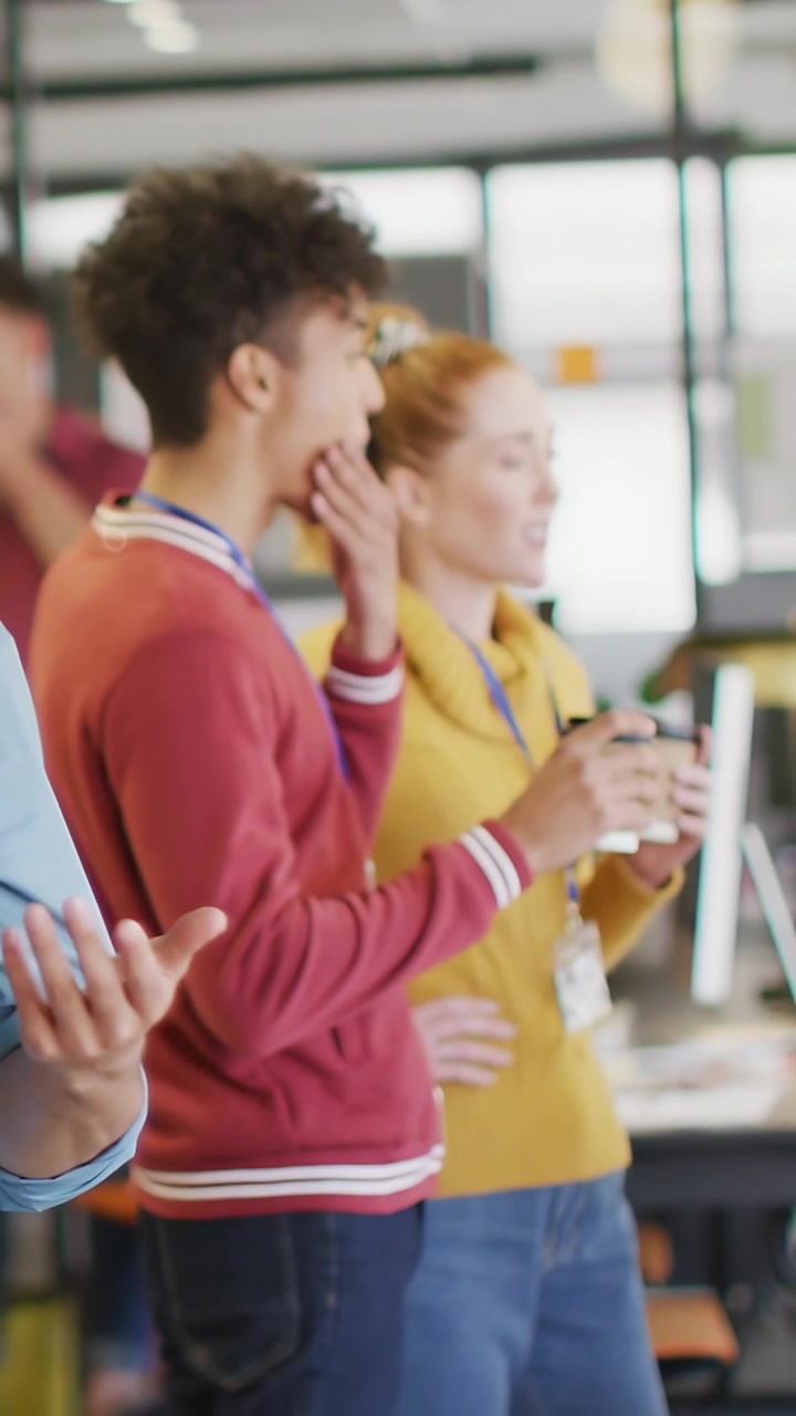 Video verticale: Personale in ufficio che guarda una demo, esaminando un grafico dati che appare sugli schermi mentre le tazze vengono sollevate.