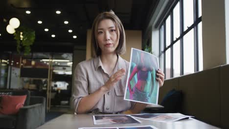 Asian-businesswoman-having-a-video-chat-going-through-paperwork-modern-office