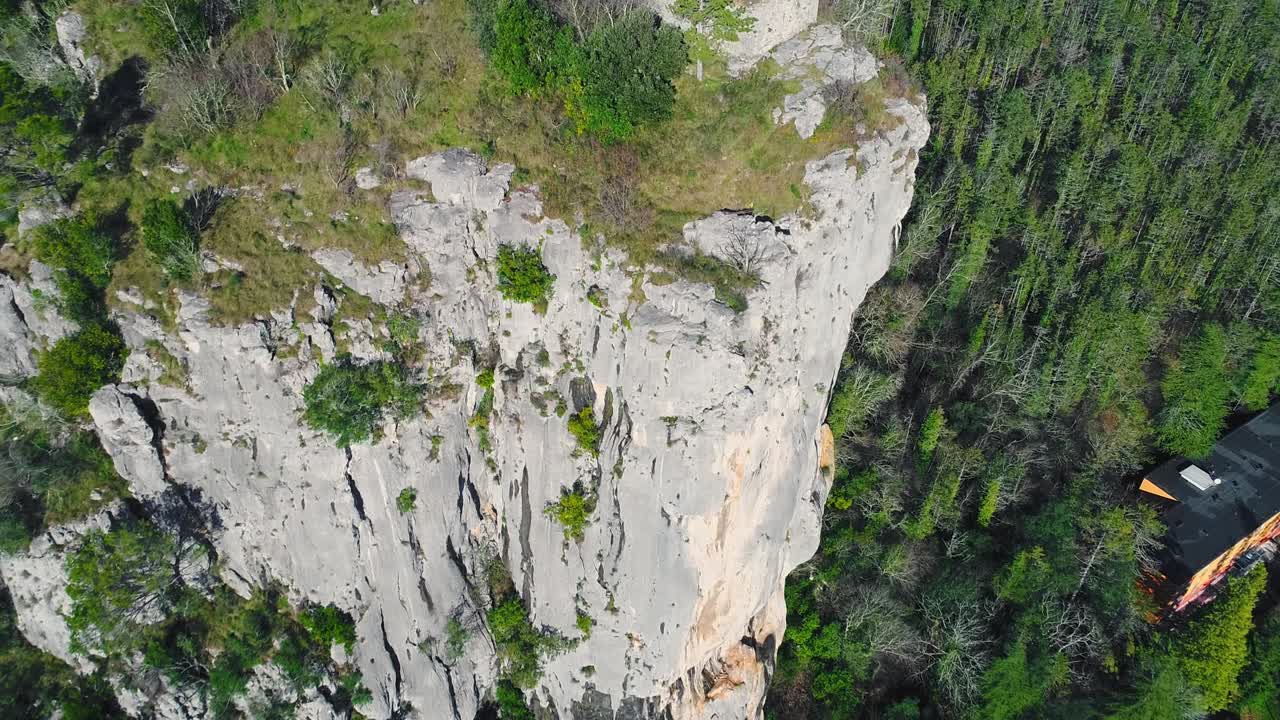 무성한 숲 위로 거대한 절벽과 유적에 접근하는 항공 촬영