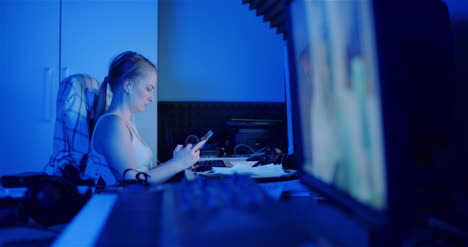woman browsing internet on smartphone while working on computer at home office 1