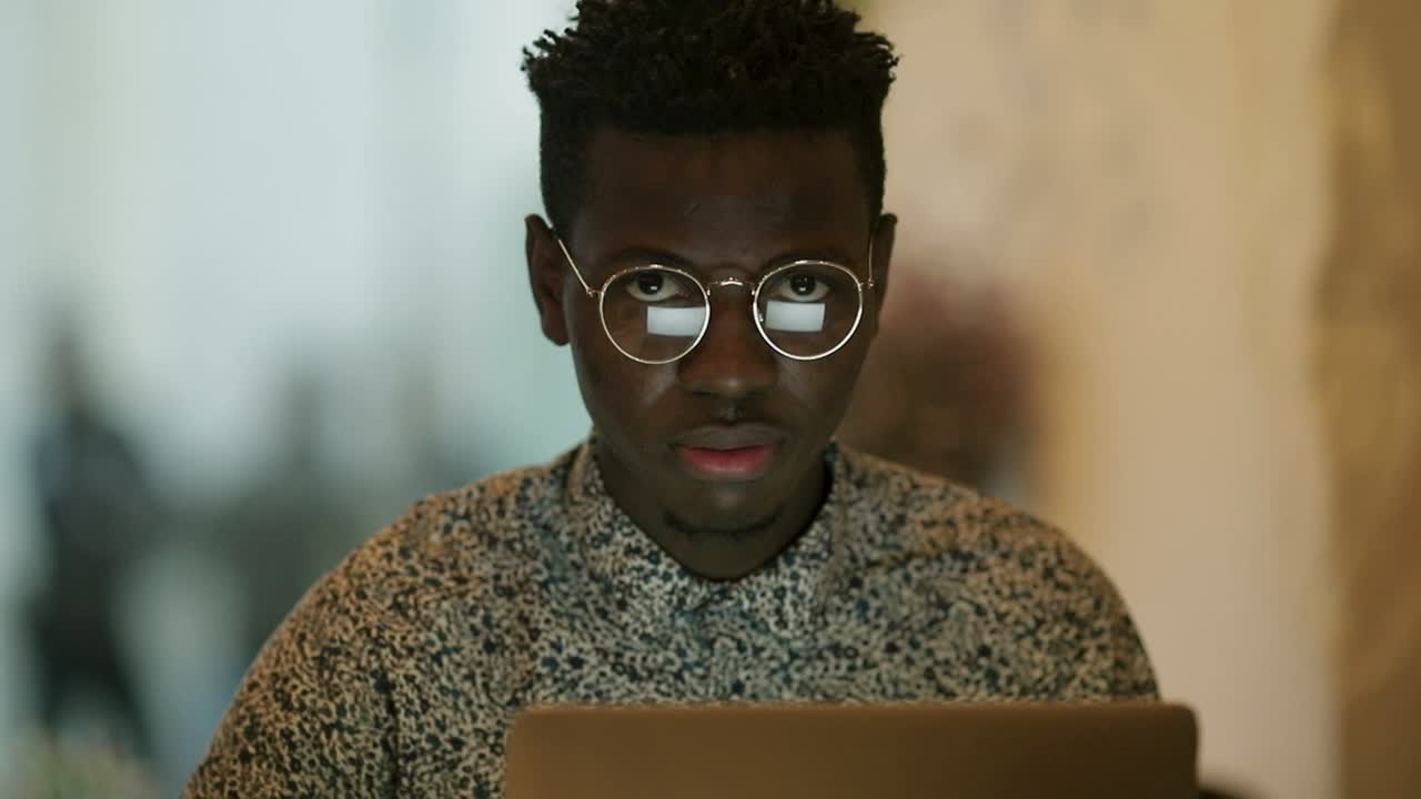 African American man using laptop and looking at camera