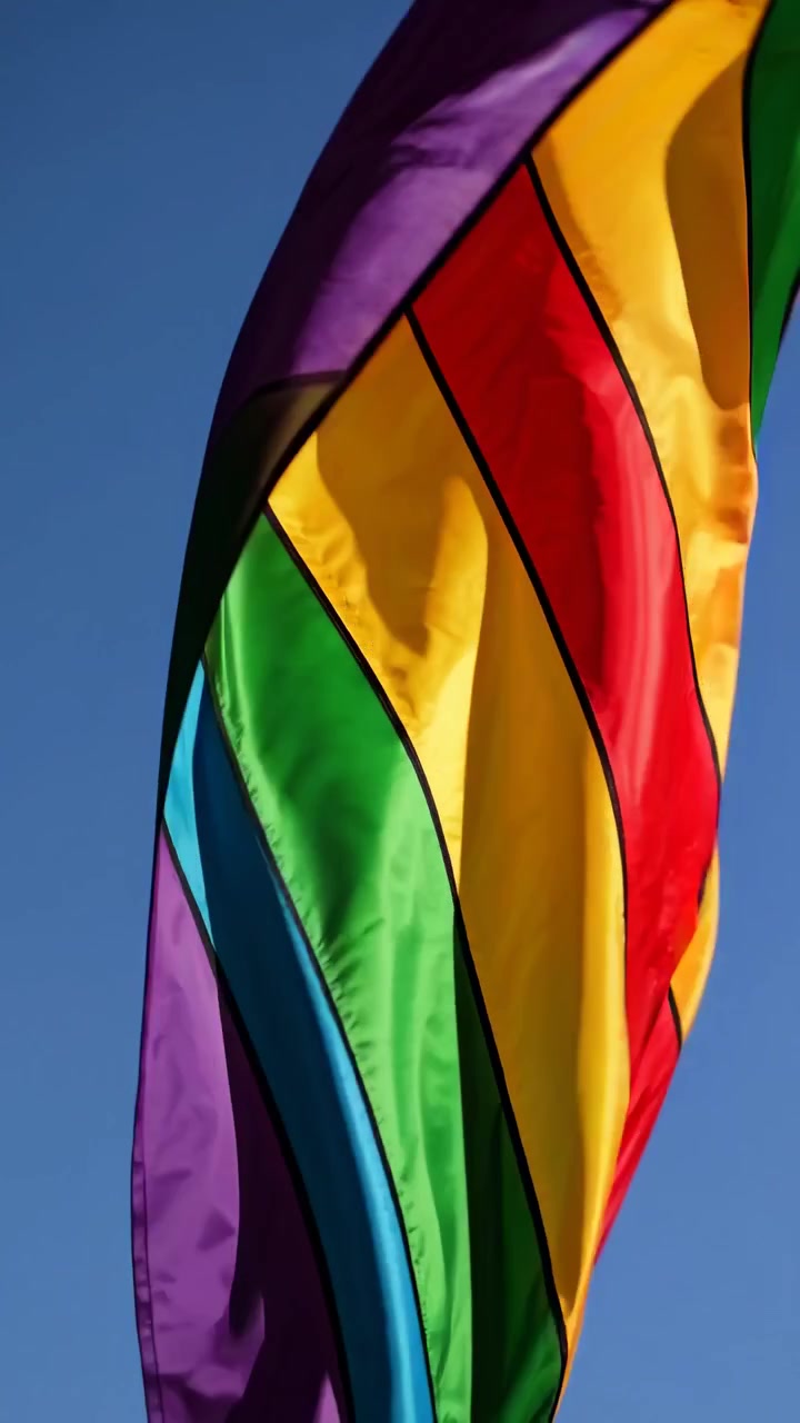 Levende regnbueflag vajer mod en klar blå himmel