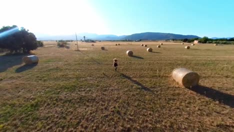chica corriendo por el campo con balas de paja