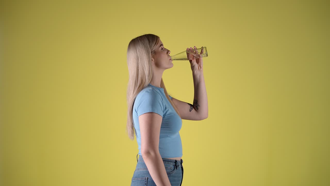 perfil lateral joven mujer rubia bebe agua refrescante de una botella de vidrio