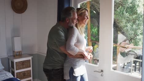 feliz pareja caucásica madura hablando y mirando por la ventana