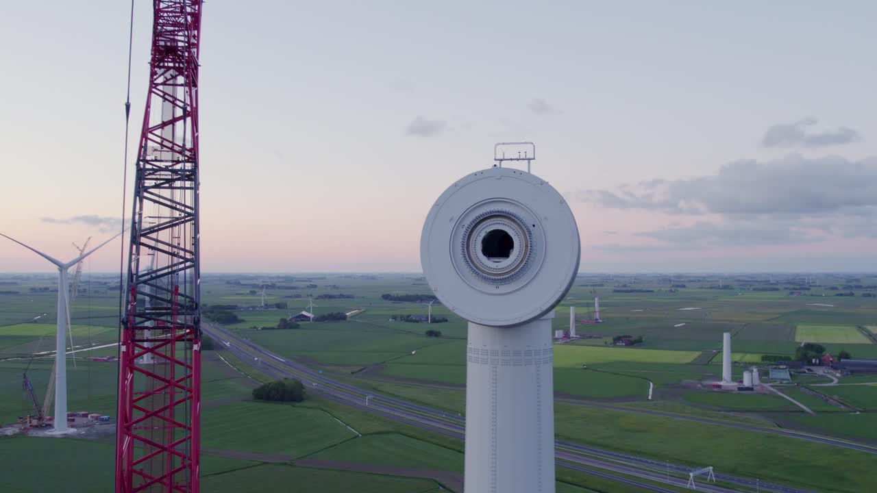 Vista all'alba dell'assemblaggio di una turbina eolica con gru, Frisia, Paesi Bassi.
