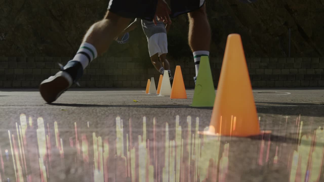 Vertikal video: En spiller i grå topp dribler, nærbilde av spilleren som utfører lave driblinger rundt kjegler for basketball.