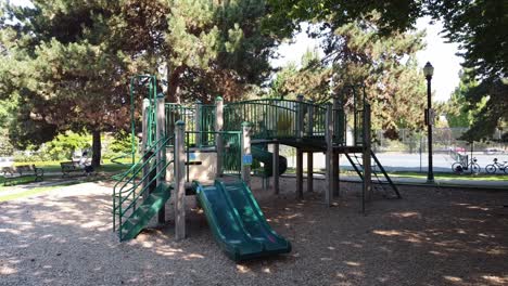 aerial hold side view of an empty deserted childrens park and tennis court with restriction notices respecting social physical distancing bylaws of covid-19 lockdown next to a victorian light post