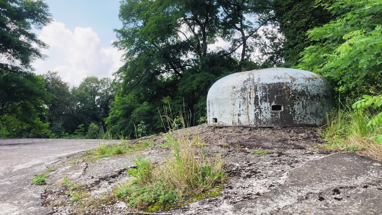 Rusty military bunker standing in the overgrown wilderness of Fort Eban-Emael