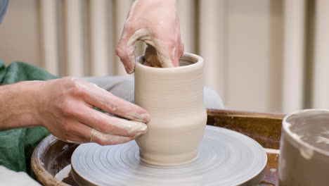 close up view of hands of a clerk modeling ceramic piece on a potter wheel in a workshop 1