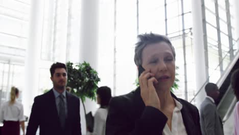 Businesswoman-talking-on-mobile-phone-in-the-lobby-at-office-4k
