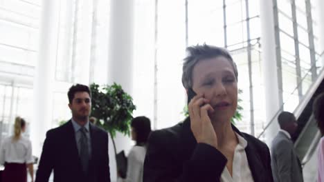 mujer de negocios hablando por teléfono móvil en el vestíbulo de la oficina 4k