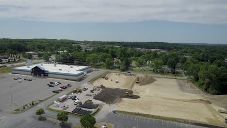 Aerial-drone-forward-moving-shot-over-road-highway-with-traffic-movment-near-mall-along-a-busy-construction-site-during-evening-time