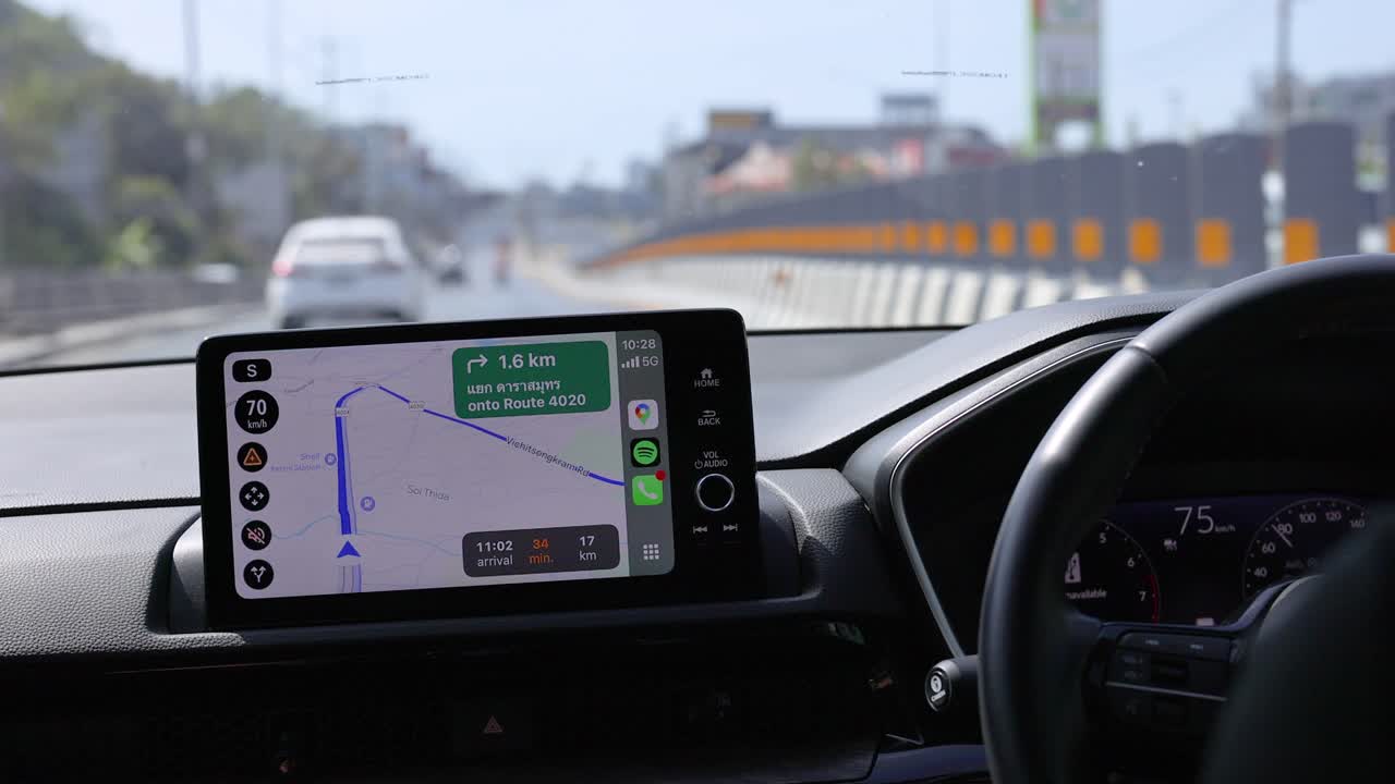 A car navigates Phuket roads using a GPS system. Bright daylight illuminates the dashboard and road ahead