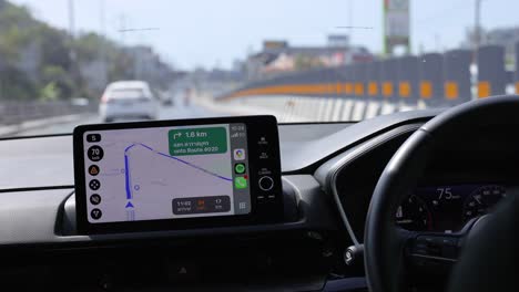 a car navigates phuket roads using a gps system. bright daylight illuminates the dashboard and road ahead