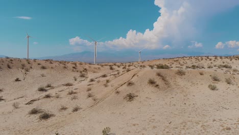 lento desplazamiento lateral de arena y colinas cubiertas de prisa cerca de una pequeña ciudad desértica y una granja eólica de energía verde