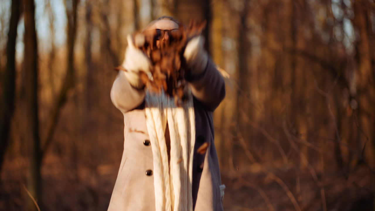 mujer feliz positiva tirando hojas en otoño en el parque 1