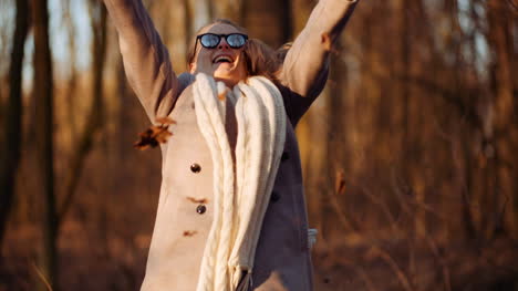 mujer feliz positiva tirando hojas en otoño en el parque 1
