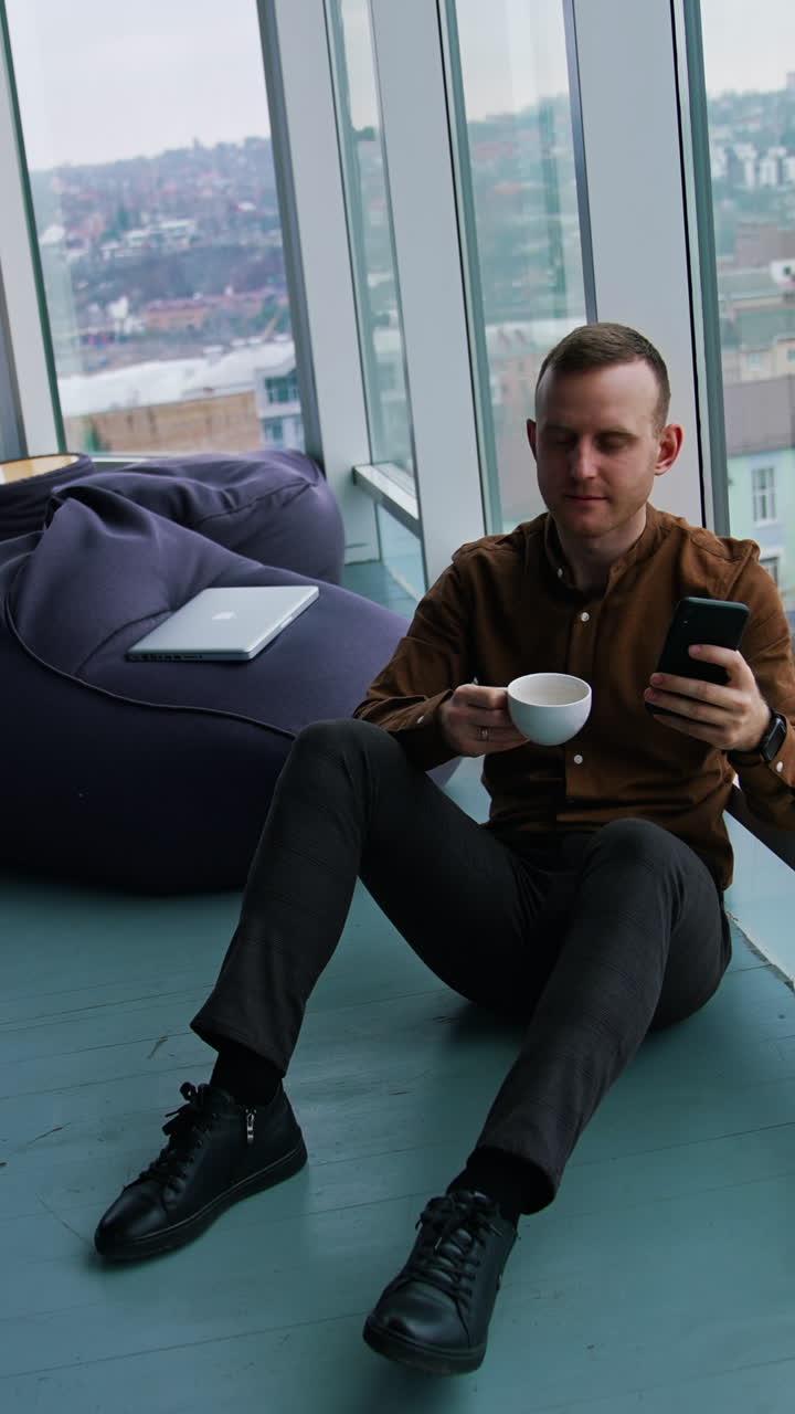 Handsome man talking on mobile phone and drinking coffee Vertical video