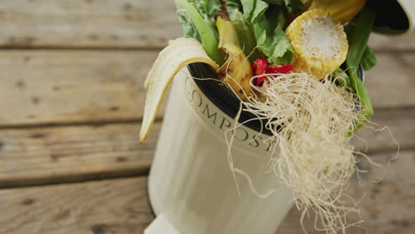 video of white compost bin with organic waste on wooden background