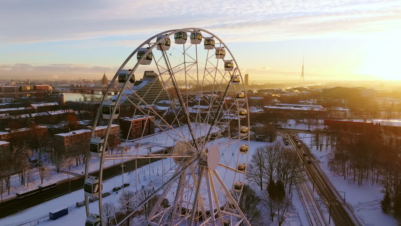 Golden sunlight lights up snowy Riga skyline with Ferris wheel in foreground