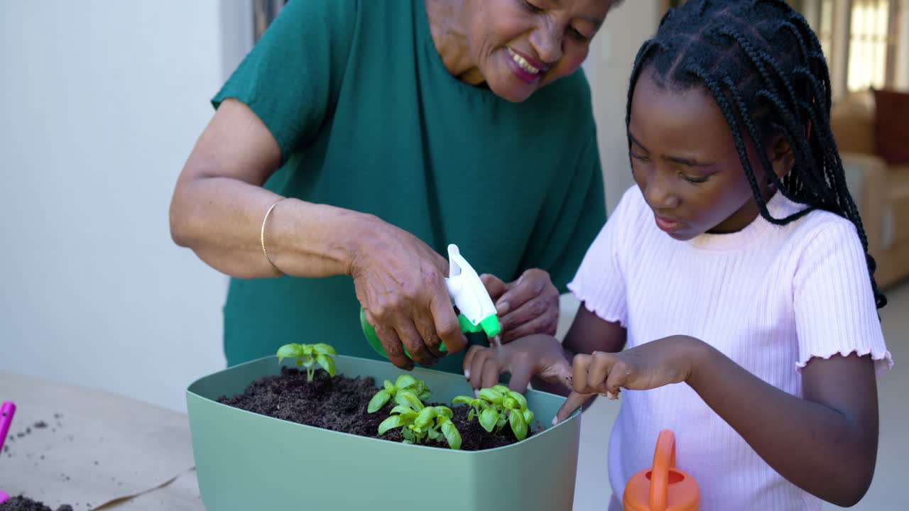 La caméra se concentre sur la jardinière, une personne âgée guide un enfant qui place et vaporise des herbes sur le porche, enseignant.