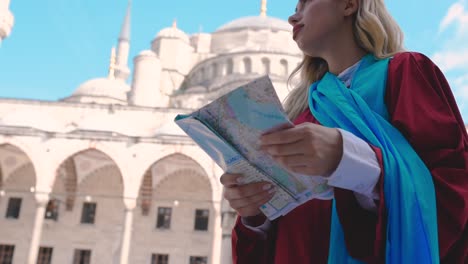 Slow-Motion:Attractive-beautiful-girl-looks-at-map-of-Istanbul-with-view-of-Sultan-Ahmet-Mosque-in-Istanbul,Turkey