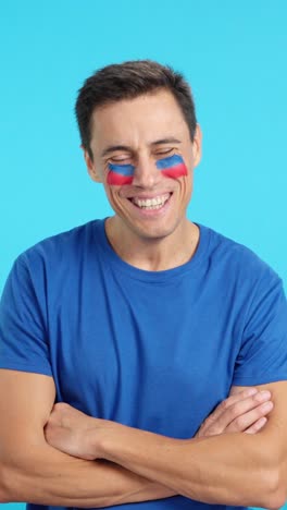 man standing with haitian flag painted on face smiling