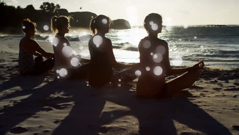 rear view of women mediating on sand