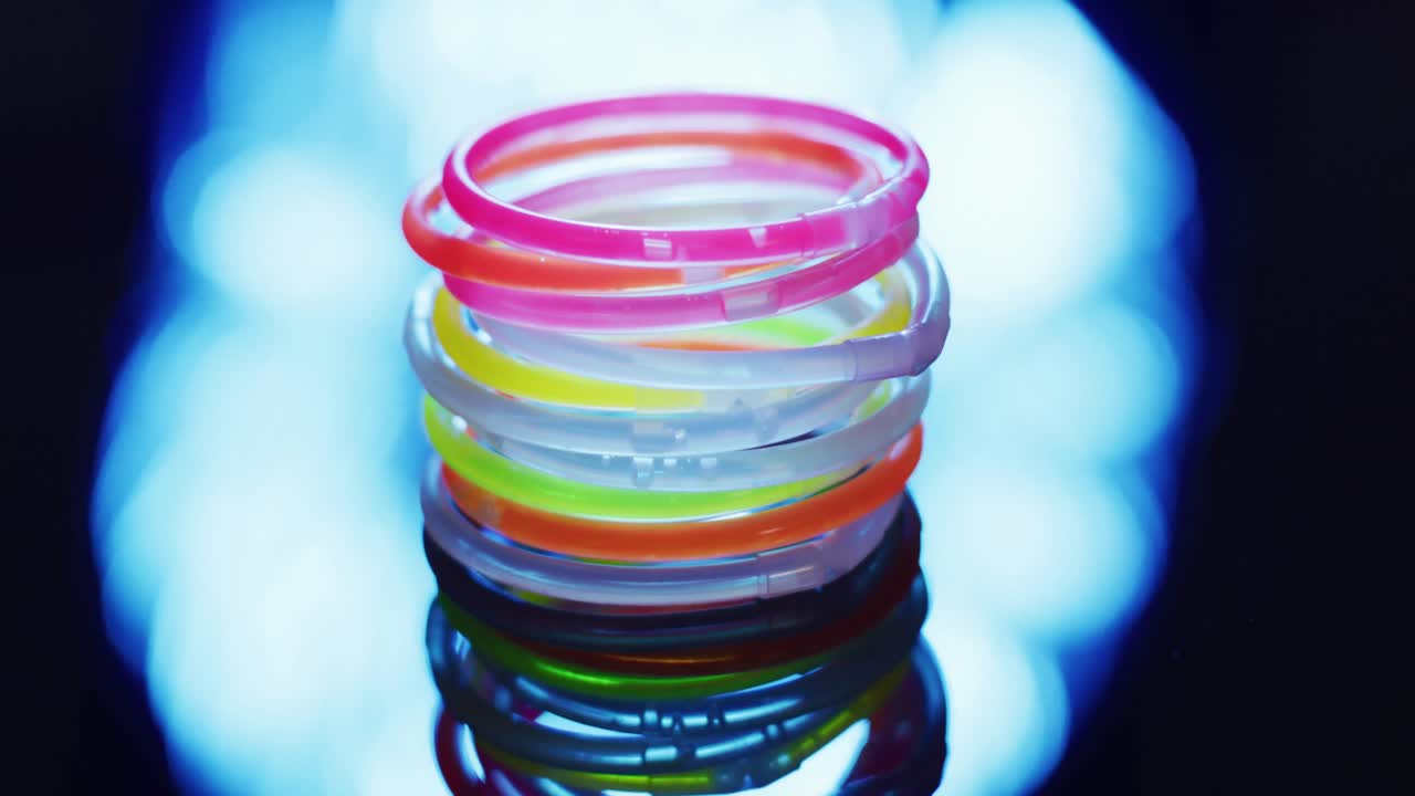 검은색 배경의 빛 반점 위에 여러 가지 다채로운 네온 빛 막대기의 애니메이션