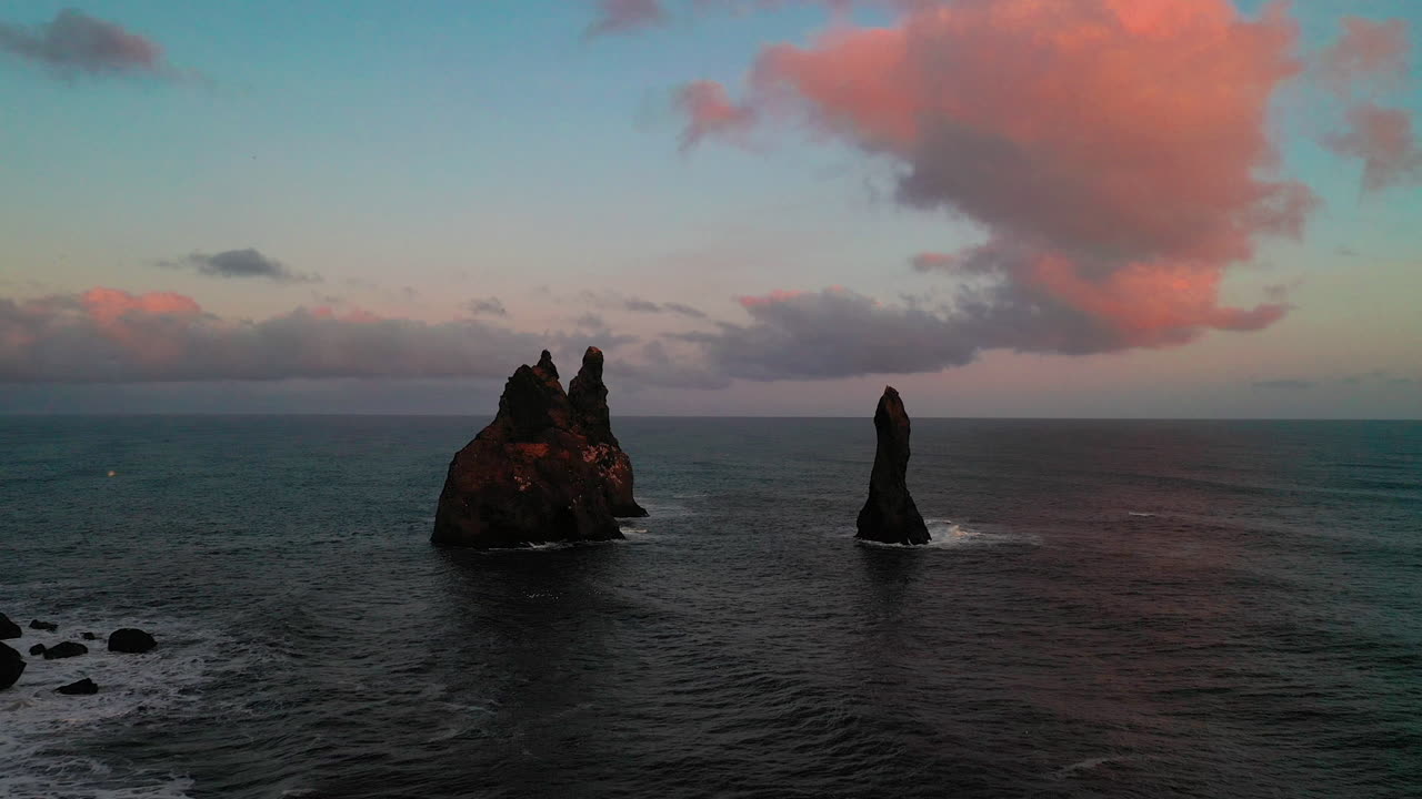 Drone che vola verso i faraglioni di basalto di Reynisdrangar nell'Islanda del Sud al tramonto - ripresa con drone.