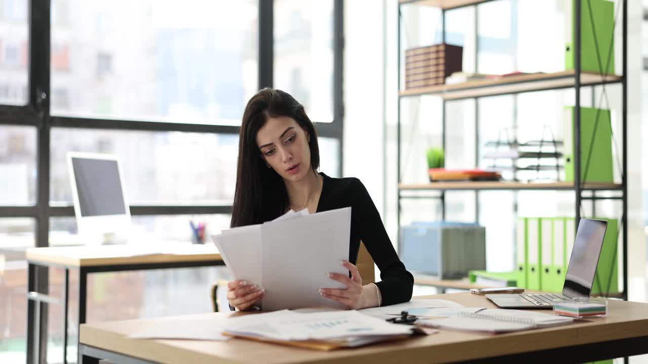 Woman displaying various emotions from concentration to boredom while working at her desk in a modern office