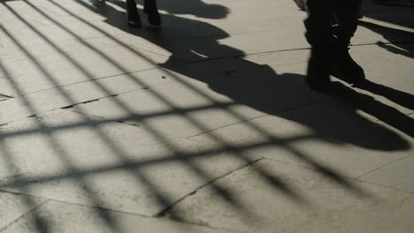 close up shoes of people walking by, grid shadow on the concrete