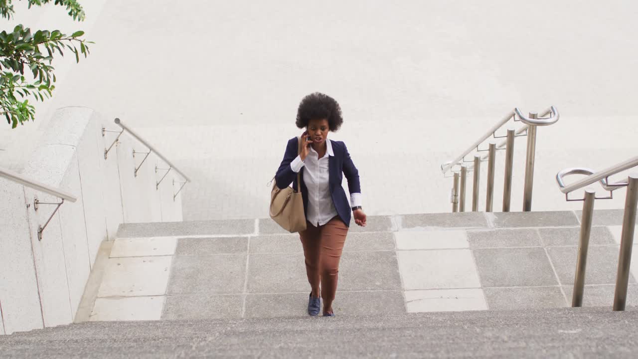 African american businesswoman walking and talking on smartphone