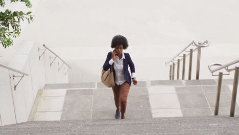 African-american-businesswoman-walking-and-talking-on-smartphone