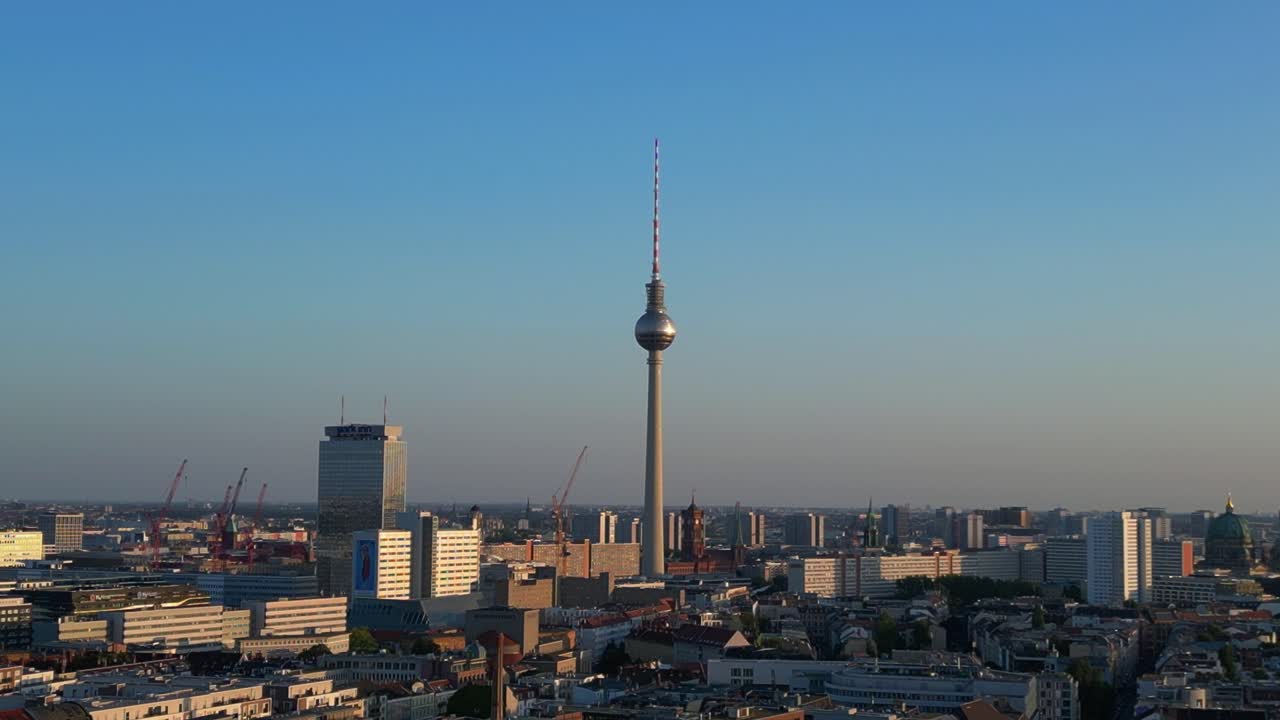 la torre de televisión de berlin de pie alto sobre la torre y el ayuntamiento rojo, bañado en el cálido resplandor de la hora de oro. increíble vista aérea vuelo volar drone inverso