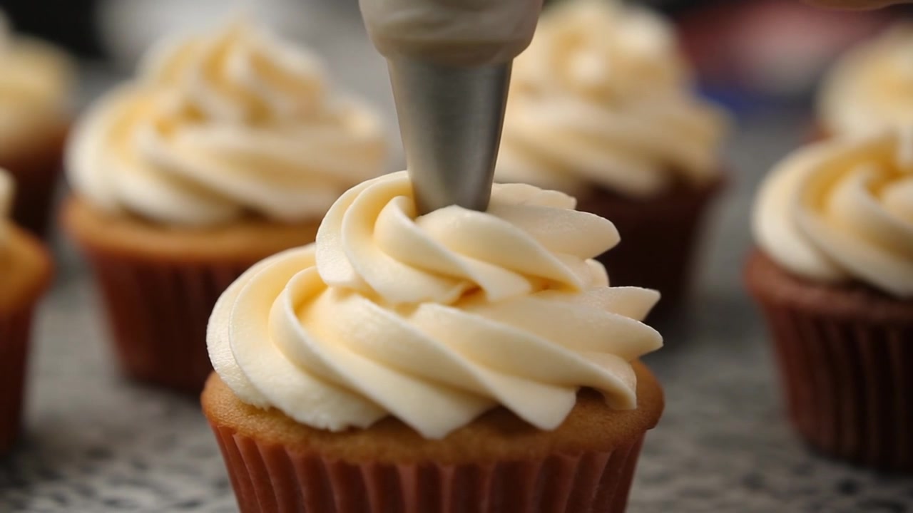 Pasticciere che decora un cupcake con glassa alla crema