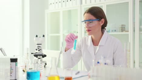 female scientist examining blue liquid in a test tube in a laboratory