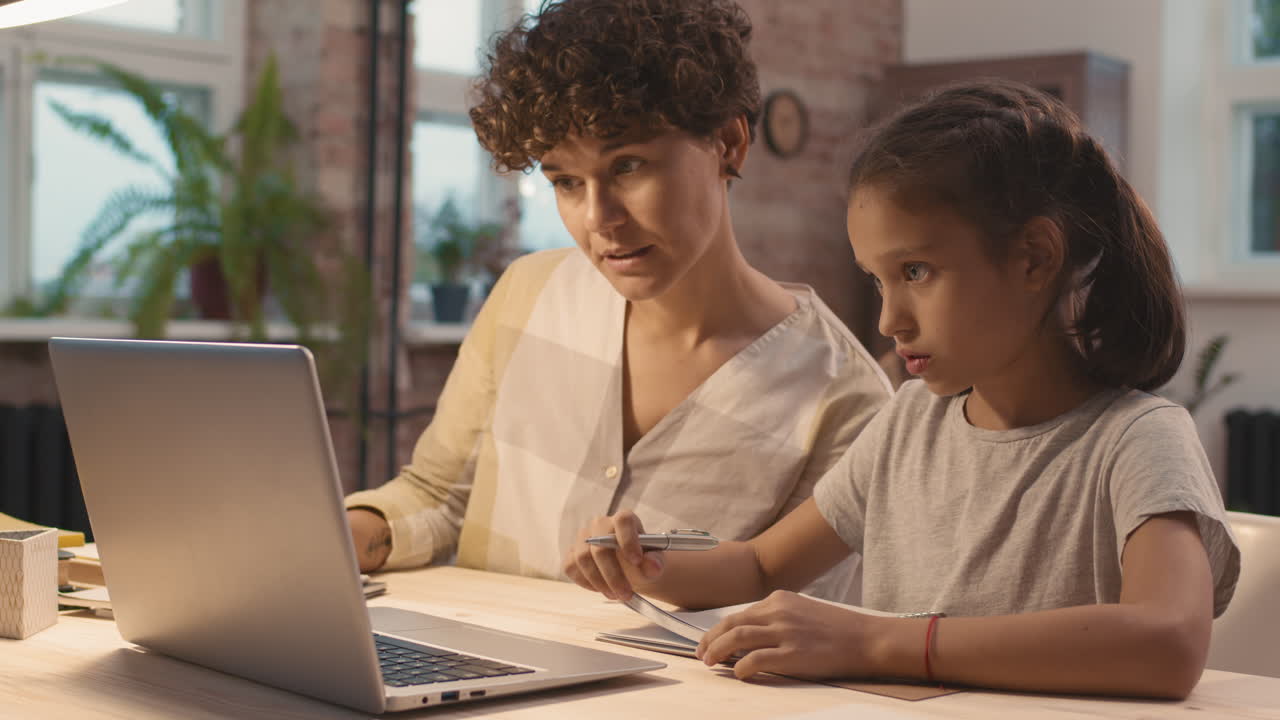 madre ayudando a su hija con la tarea en la computadora portátil