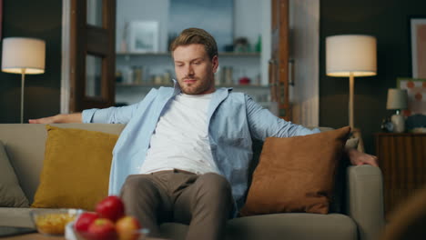 relaxed man sitting sofa at home. carefree lazy guy chilling cozy couch at house