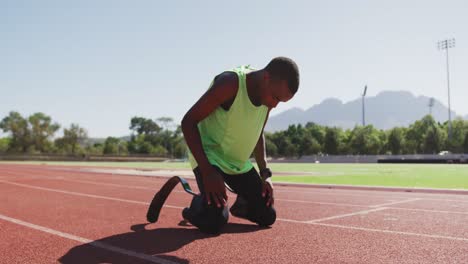 disabled mixed race man with prosthetic legs sitting on race track and cheering for himself